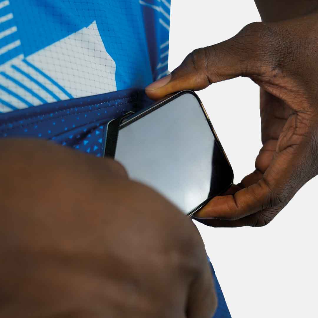 Pessoa a colocar telemóvel num bolso azul de equipamento desportivo com padrões brancos e azuis
