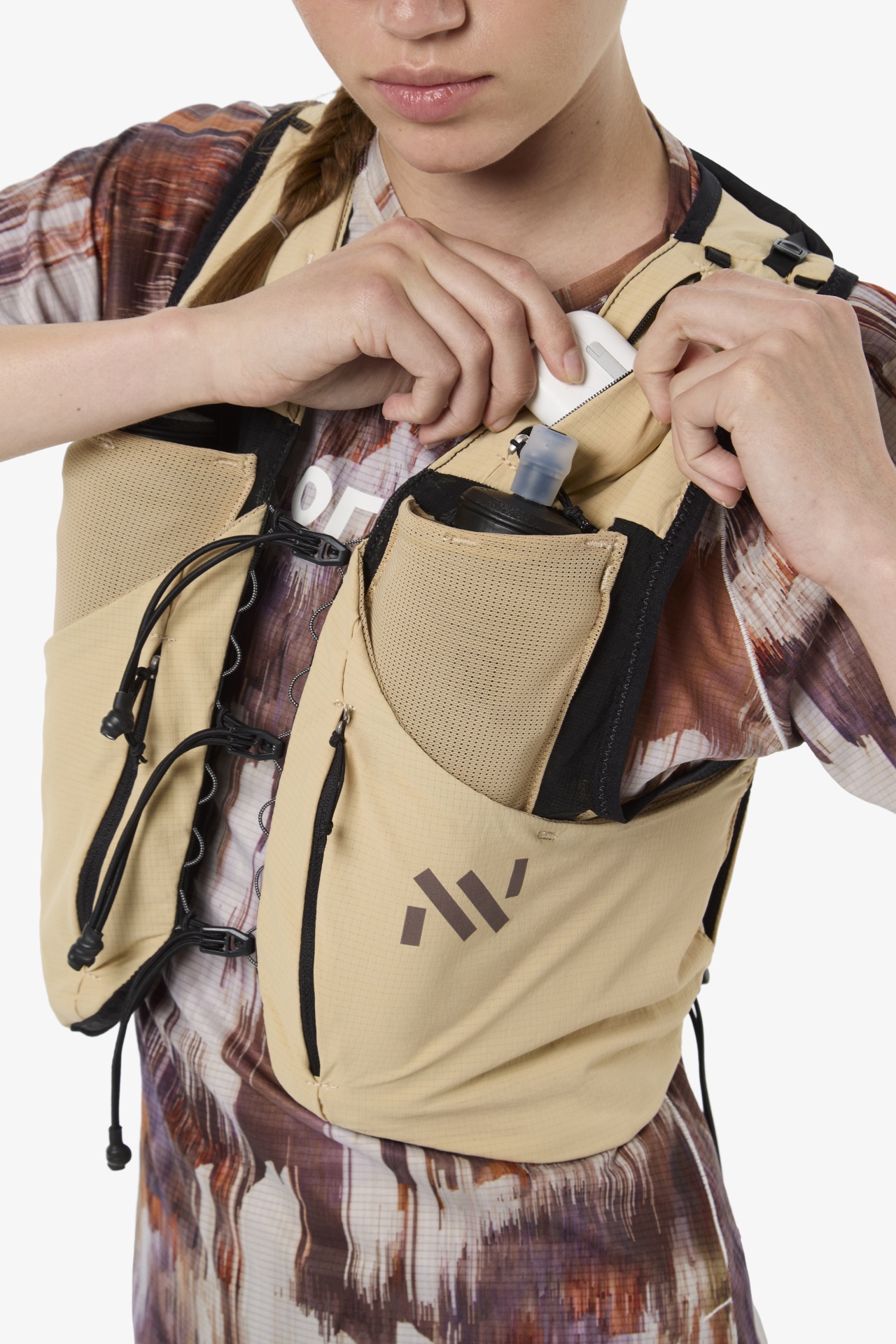 Colete desportivo bege com bolsos e fechos pretos usado sobre t-shirt estampada