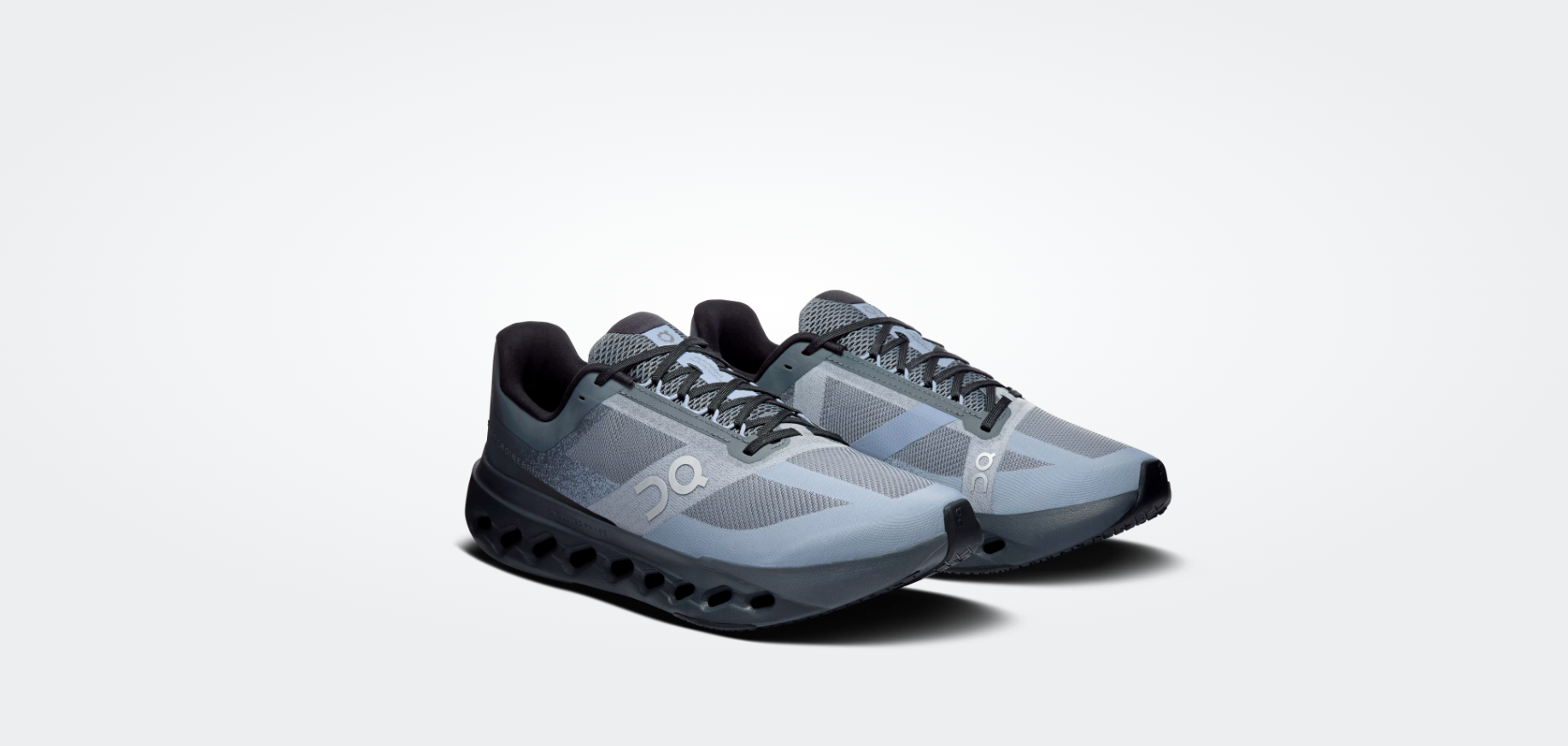 Par de sapatilhas desportivas cinza e preto com sola perfurada e logo ON