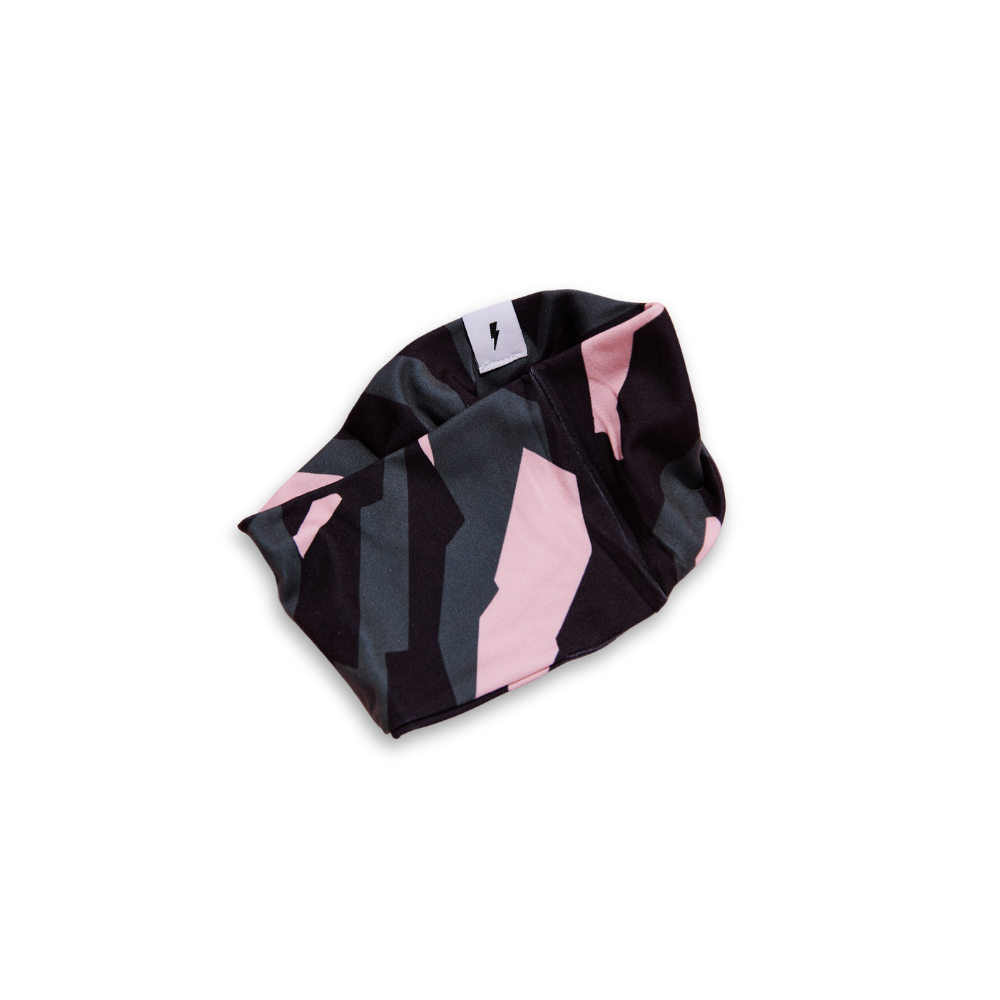 Faixa de tecido com padrão geométrico em preto, cinza e rosa, com etiqueta branca e símbolo de raio preto