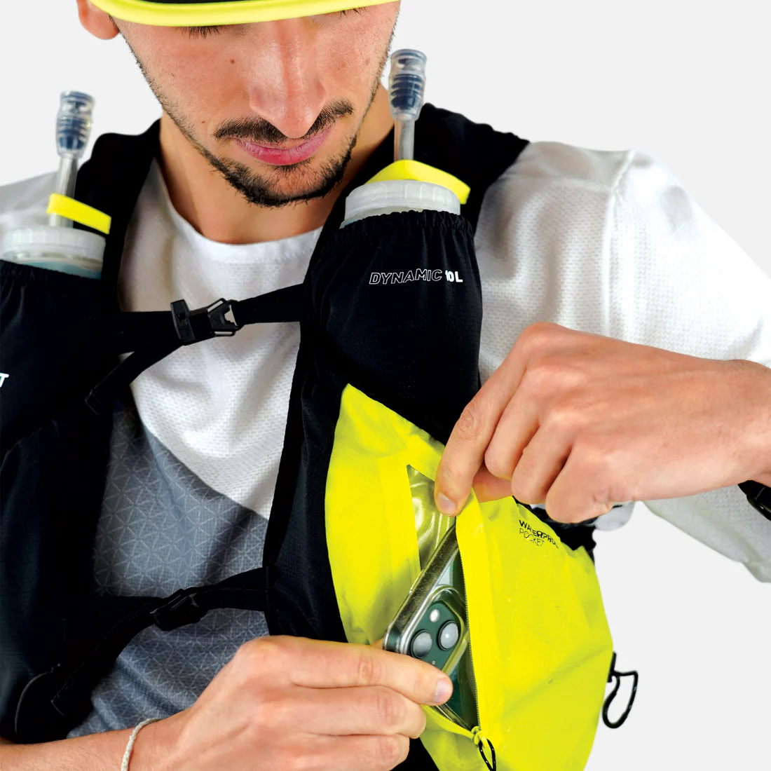 Mochila de hidratação preta e amarela com reservatórios de água e bolso frontal aberto, telemóvel visível