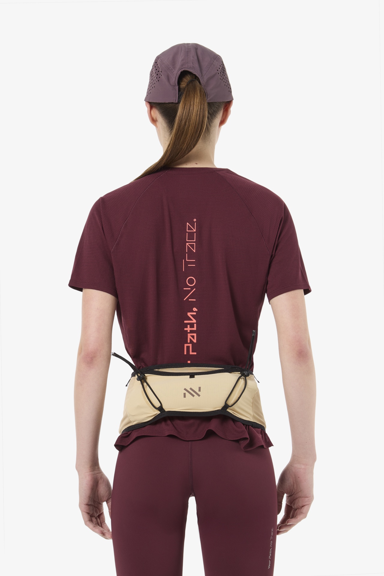 Pessoa de costas com boné roxo e roupa desportiva roxa com texto vertical na t-shirt