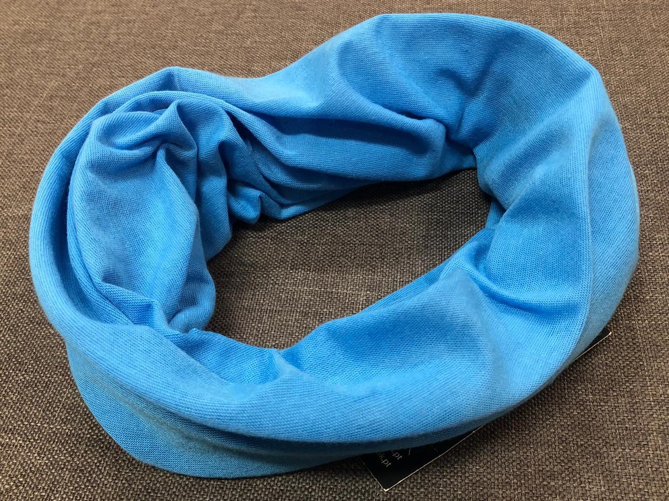 Cachecol tubular azul claro sobre fundo castanho.