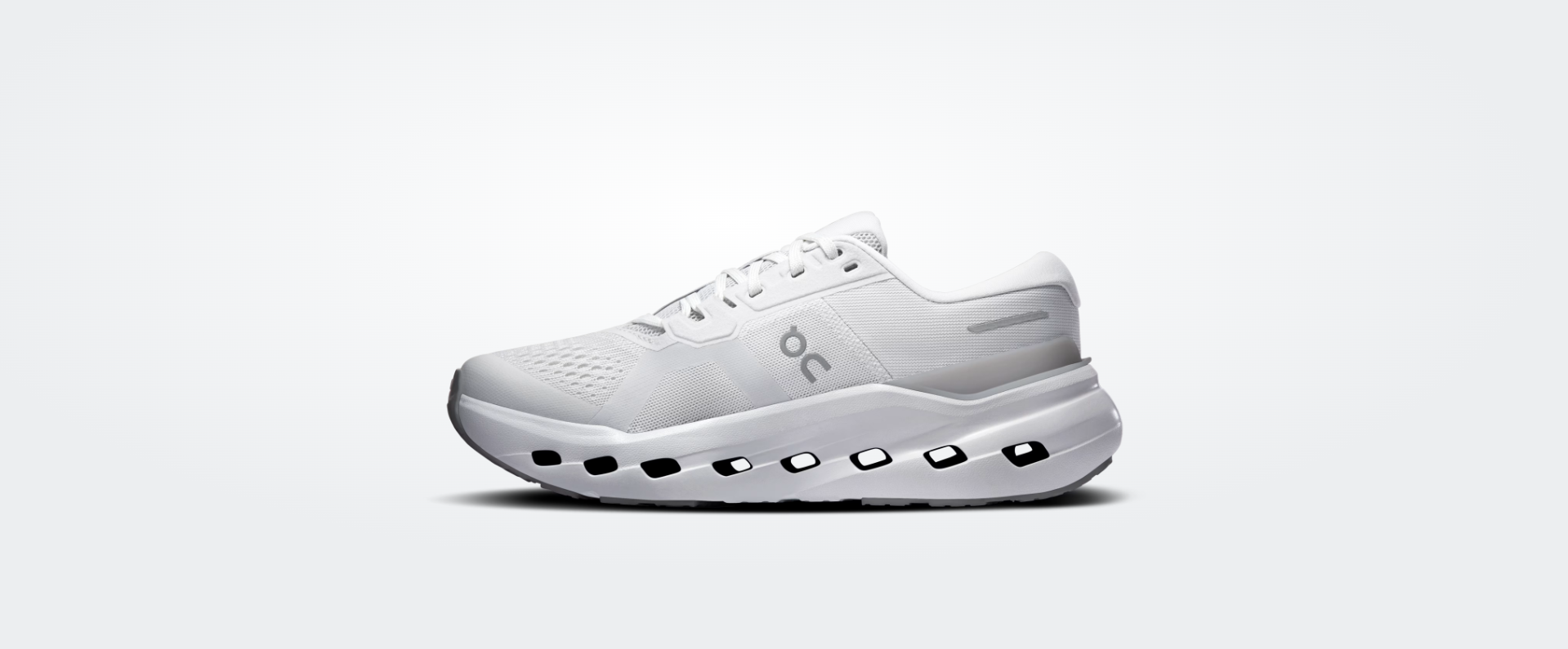 Tênis desportivo branco com sola perfurada e logo oc cinzento na lateral