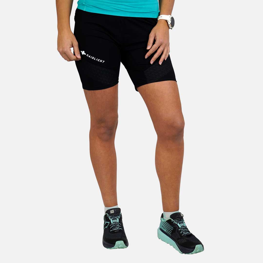 Calções pretos com texto 'RADI LIGHT' usados por pessoa com ténis e camiseta azul