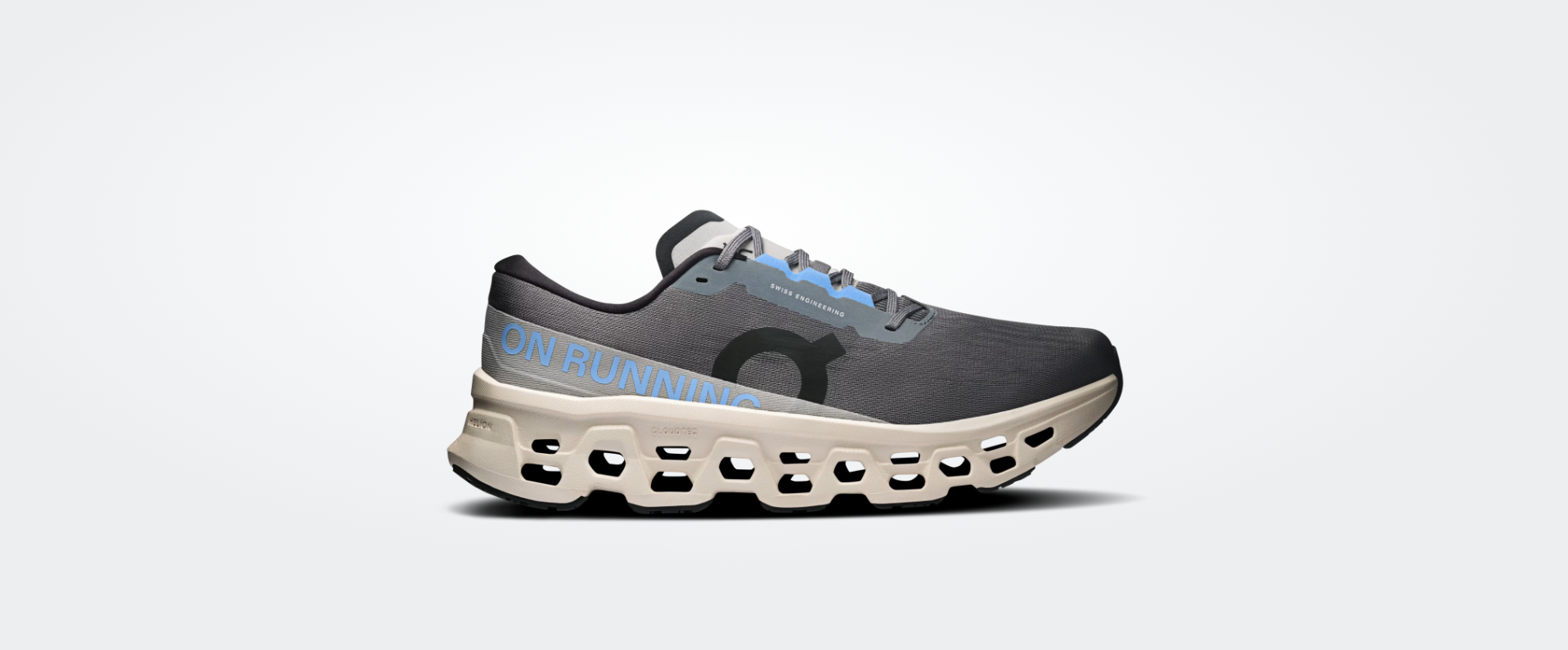 Tênis desportivo cinza e preto com sola branca perfurada e texto ON RUNNING