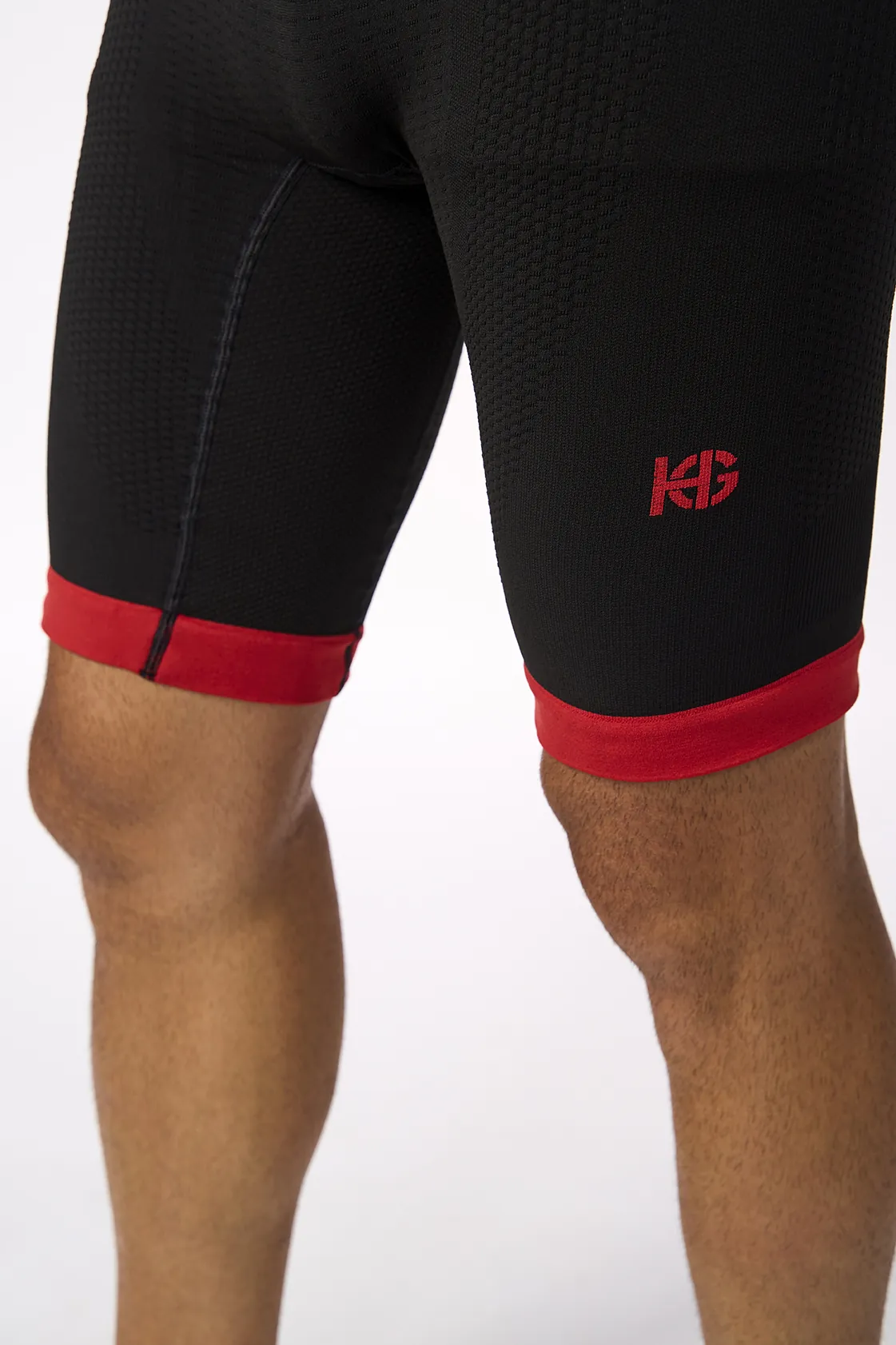 Calções desportivos pretos com bainha vermelha e logotipo KG vermelho.