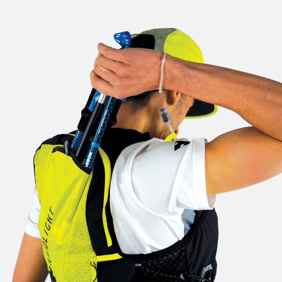 Mochila desportiva amarela e preta com bastões de caminhada azuis sobre fundo branco