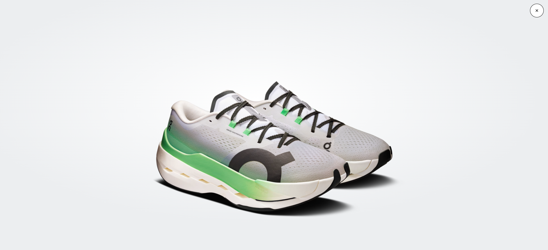 Sapatilhas desportivas brancas com verde e preto em fundo cinzento claro