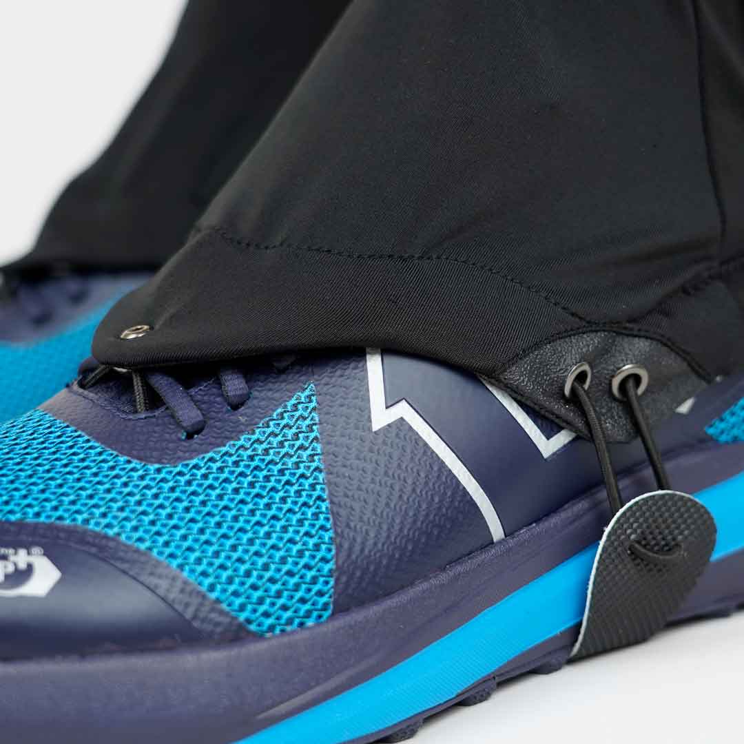 Tênis desportivo azul e preto com sola azul e calças pretas com cordão no tornozelo