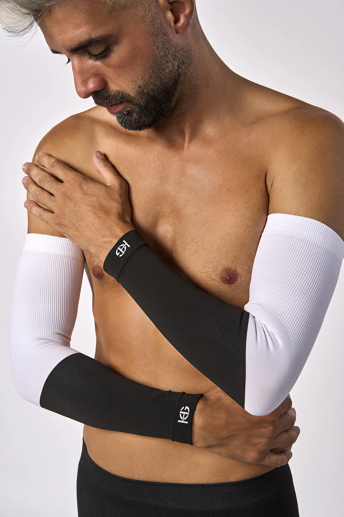 Homem usando mangas de compressão preta e branca com logotipo HS