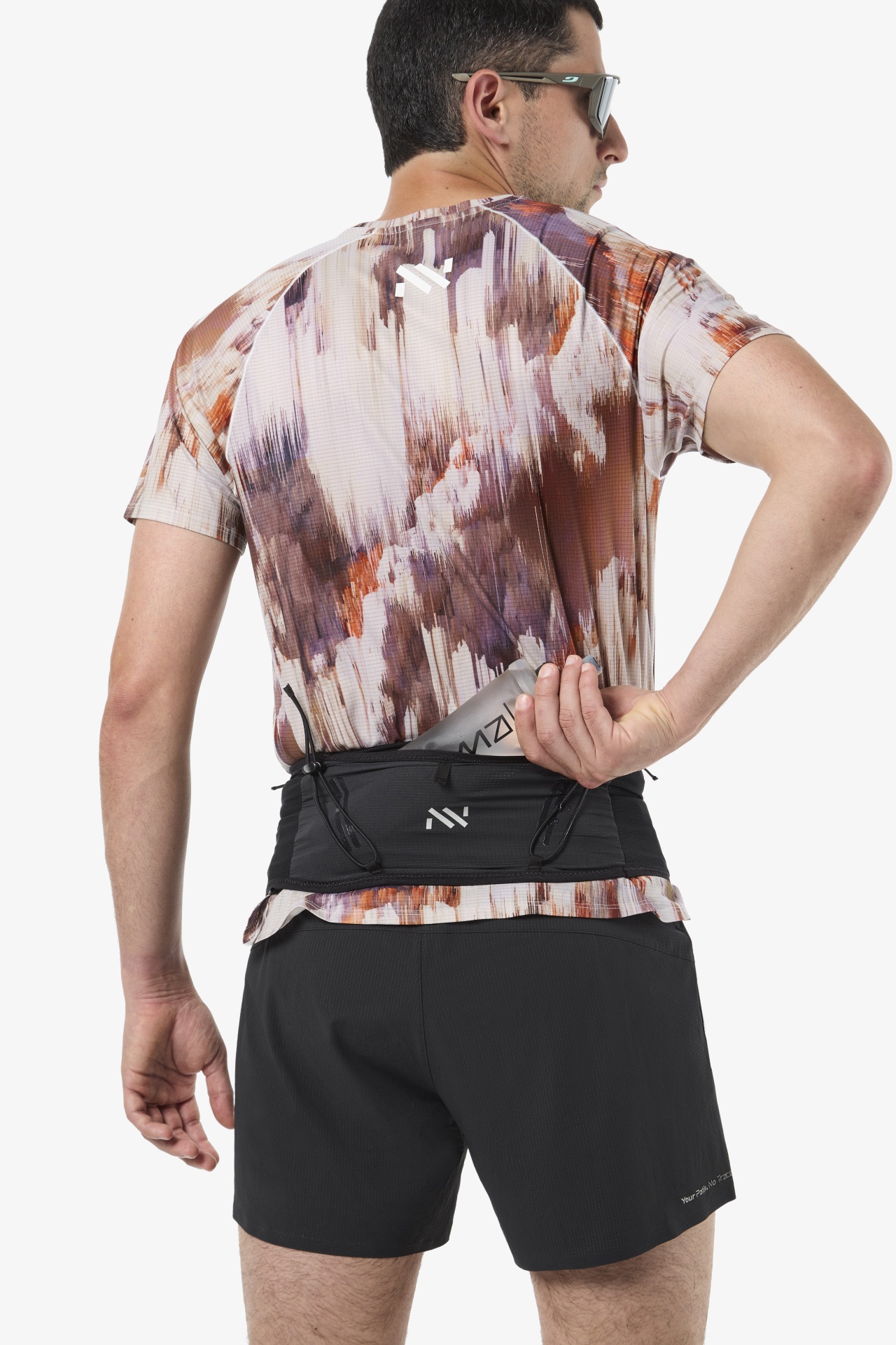 Homem com t-shirt desportiva estampada, calções pretos e cinto para corrida a guardar uma garrafa