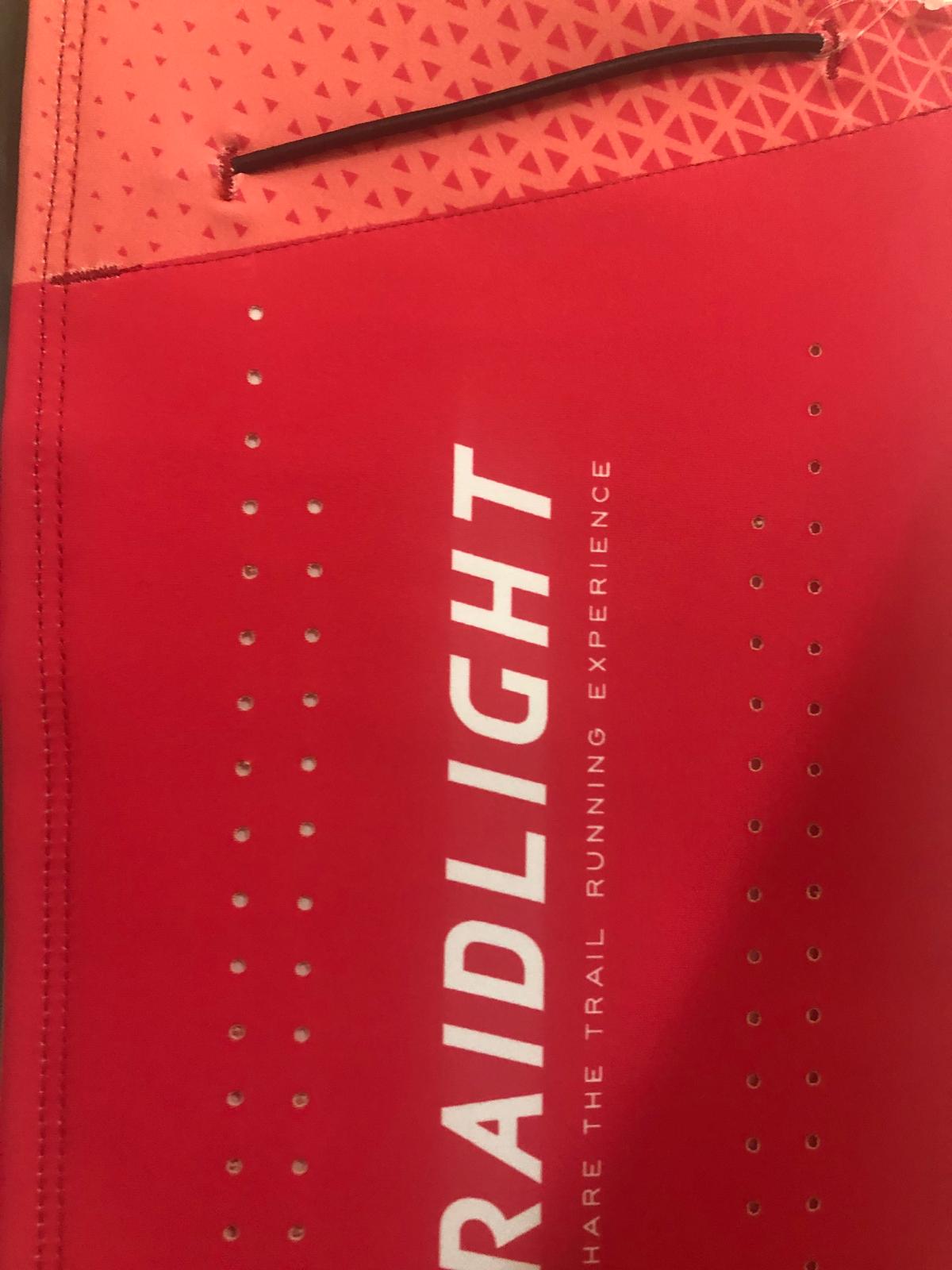 Equipamento de corrida vermelho e cor-de-laranja com texto branco e orifícios pequenos.