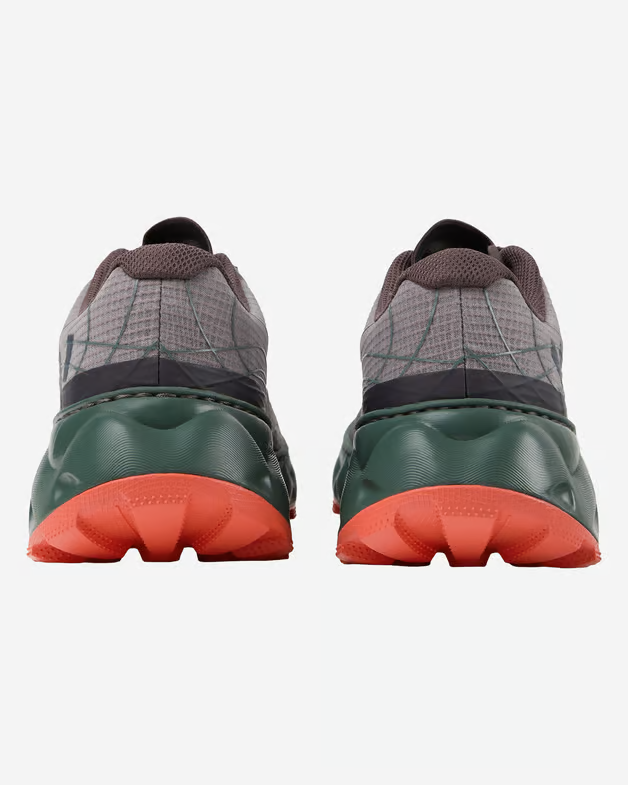 Ténis desportivos cinzentos com sola verde escura e sola de borracha laranja vistos de trás