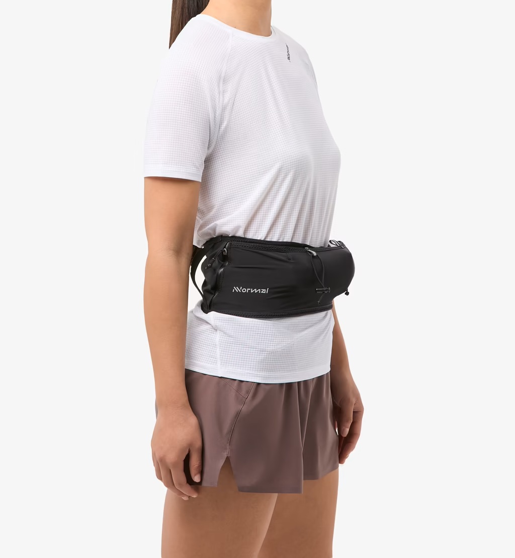 Mulher com t-shirt branca, calções castanhos e bolsa de cintura preta Marmot