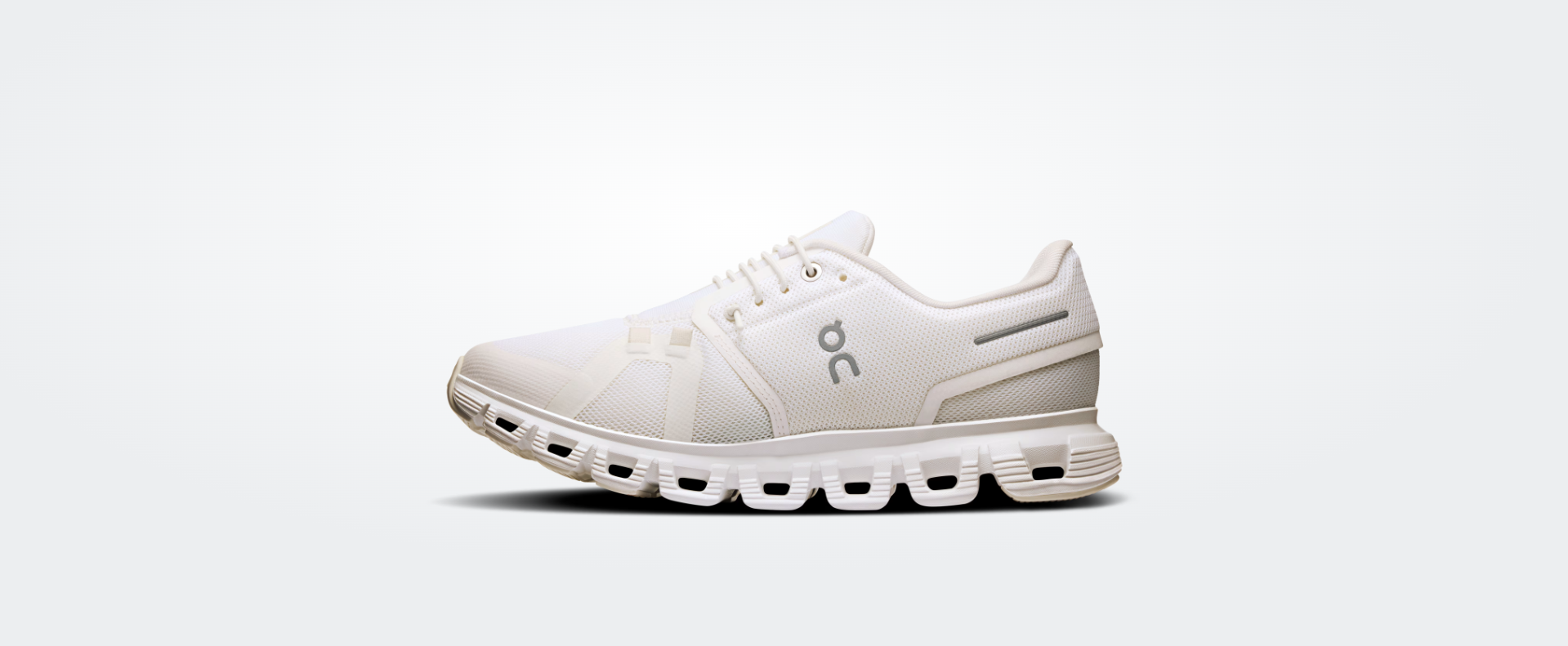 Ténis desportivo branco com sola distintiva e símbolo on cinzento.