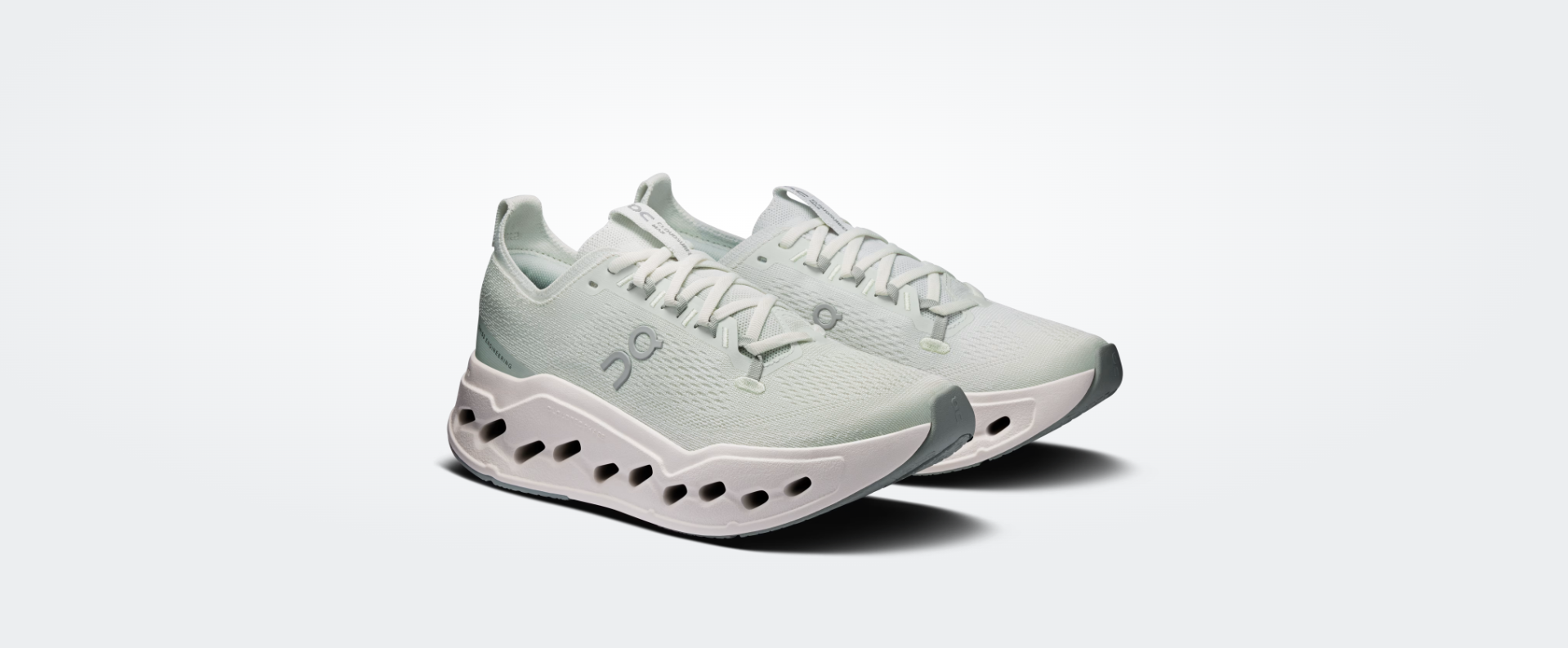 Sapatilhas desportivas brancas com detalhes cinza e sola branca com cavidades.