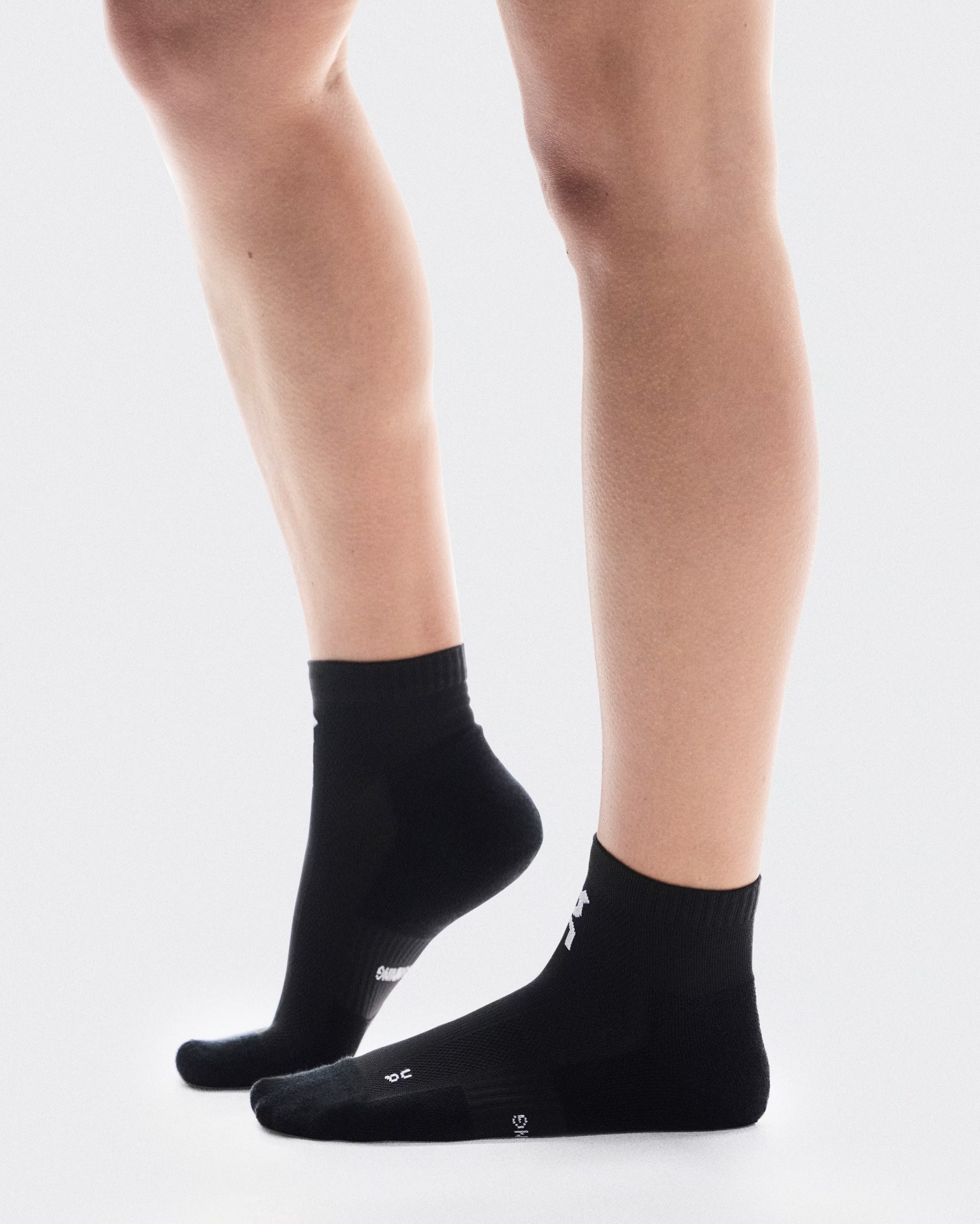 Par de meias pretas com texto branco usadas num pé humano