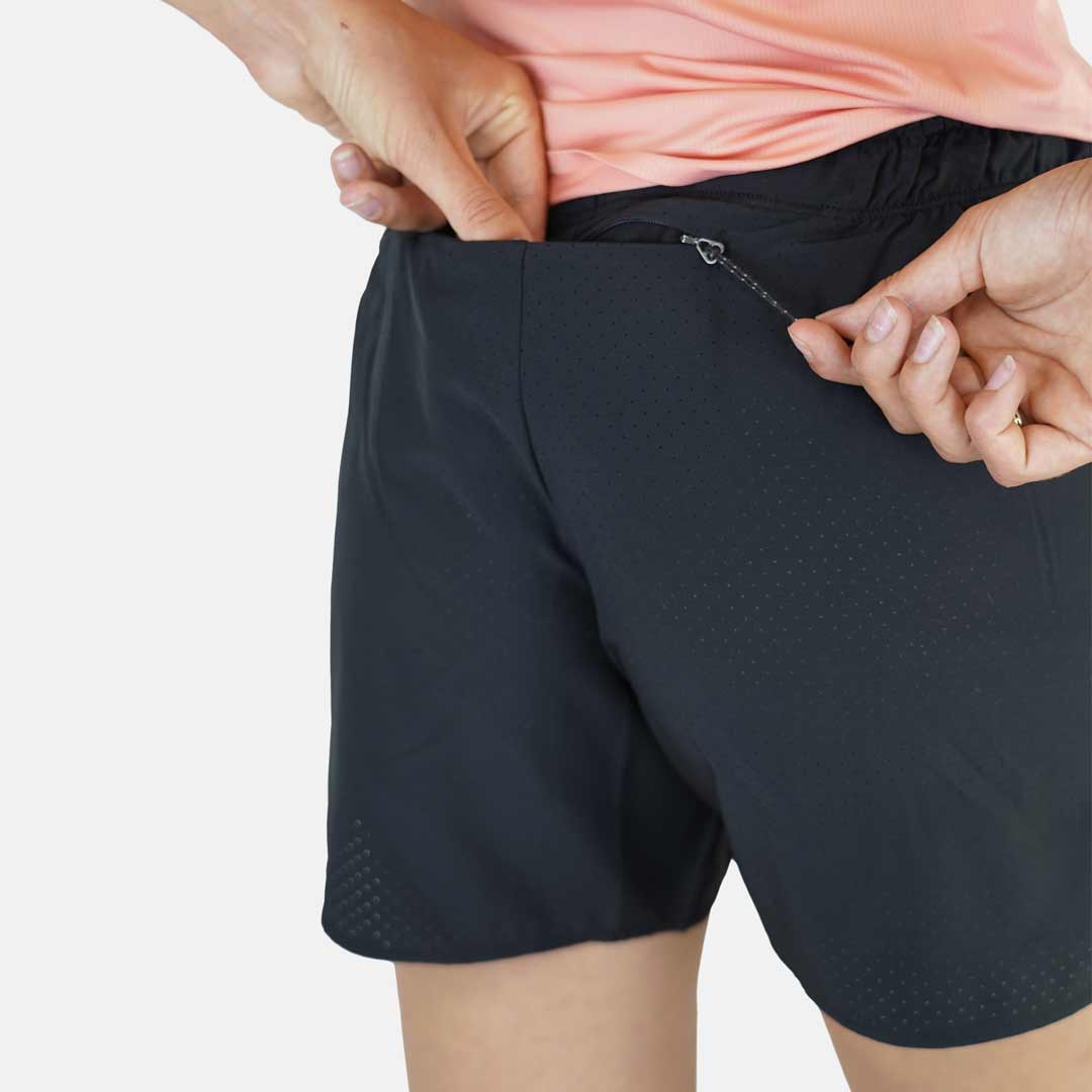 Calções pretos com bolso fecho, padrão perfurado, usados com camisa rosa