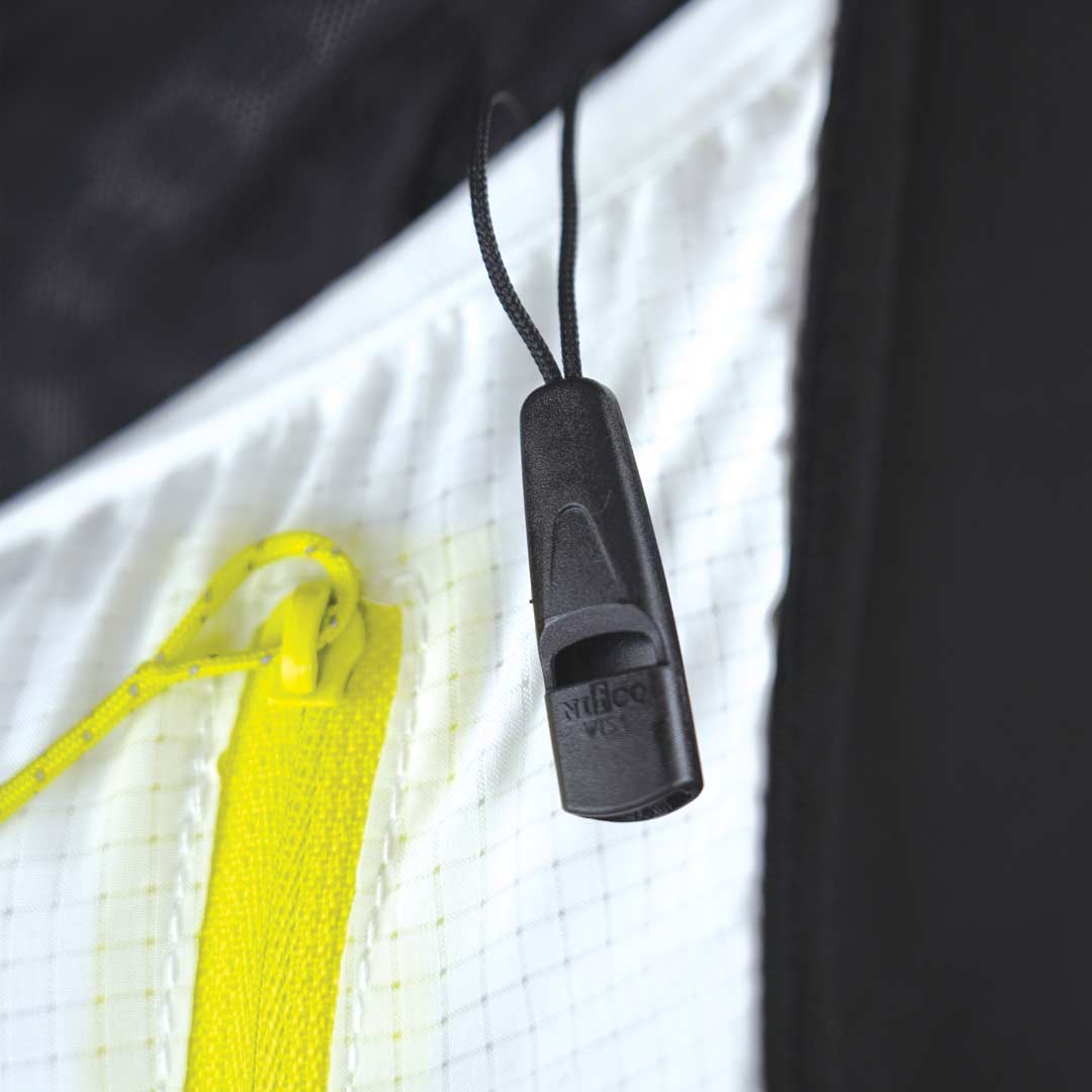 Apito preto pendurado em tecido branco com cordão amarelo e fundo preto