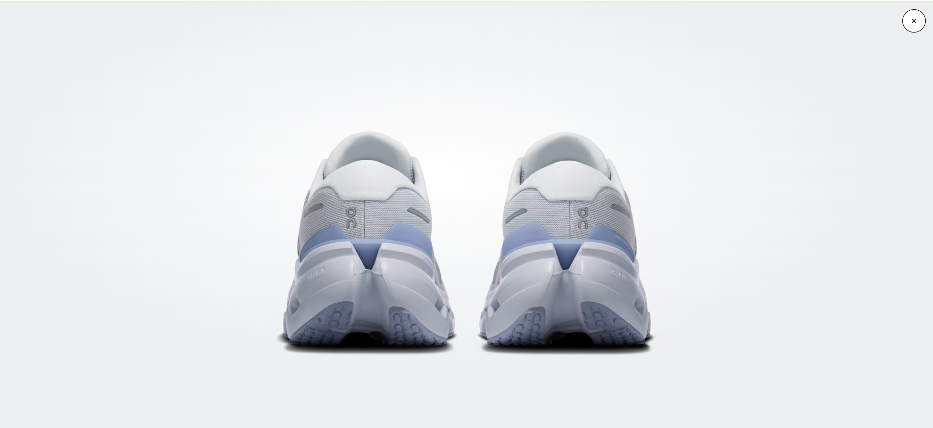 Sapatilhas desportivas brancas e cinzentas com detalhes azuis vistas de trás