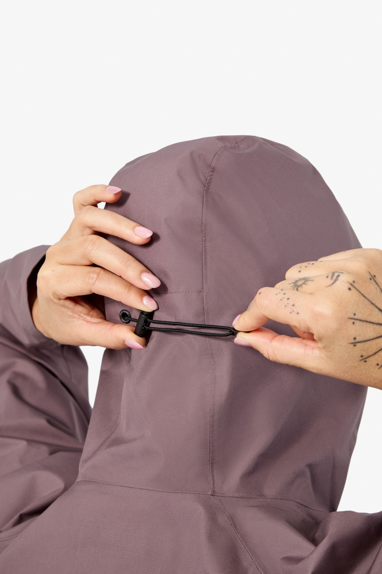 Casaco com capuz lavanda com cordão de ajuste preto e mãos femininas ajustando o capuz