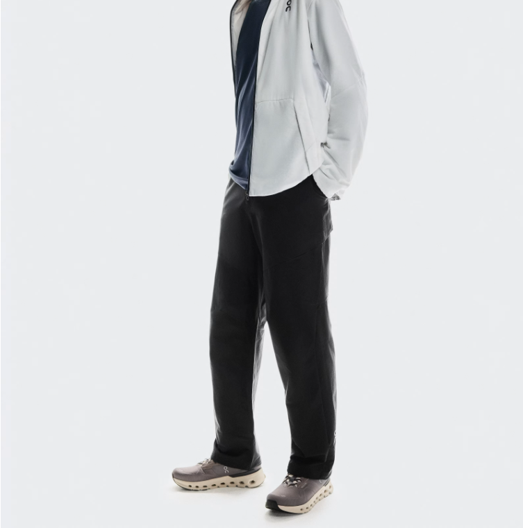 Pessoa vestindo casaco branco, t-shirt azul, calças pretas e ténis cinza