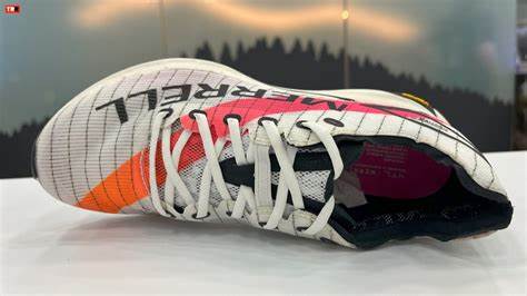 Ténis desportivo branco com apontamentos laranja e rosa e texto 'MERRELL'