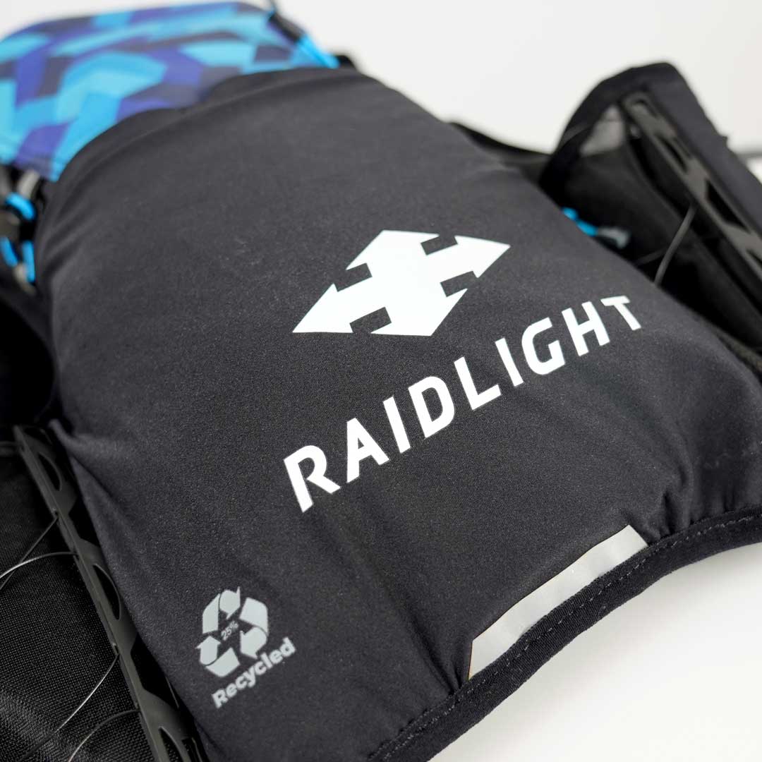 Mochila preta RAIDLIGHT com símbolo de reciclagem e tecido azul preto ao fundo