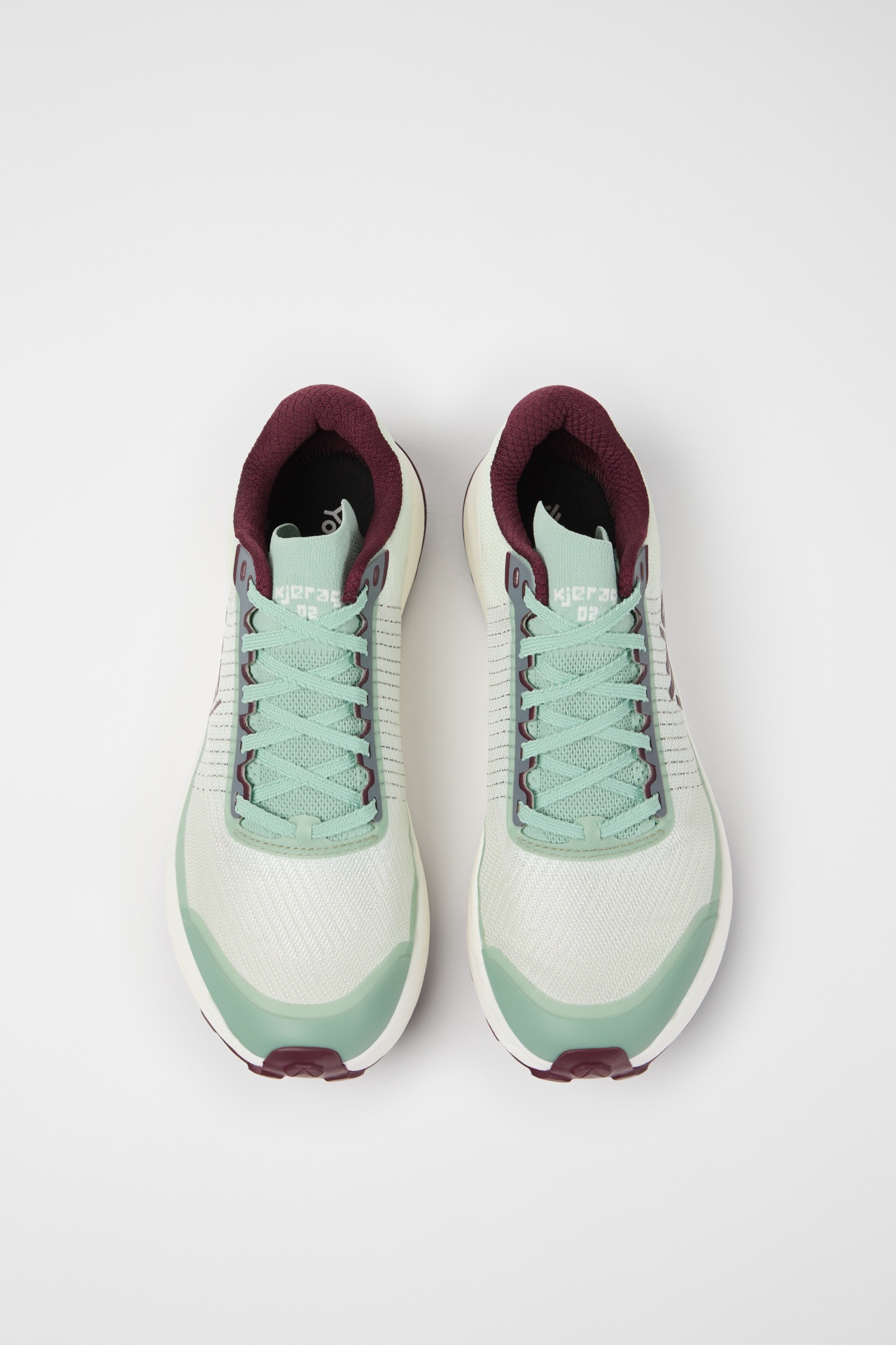 Sapatilhas desportivas brancas e verdes com interior bordeaux sobre fundo branco