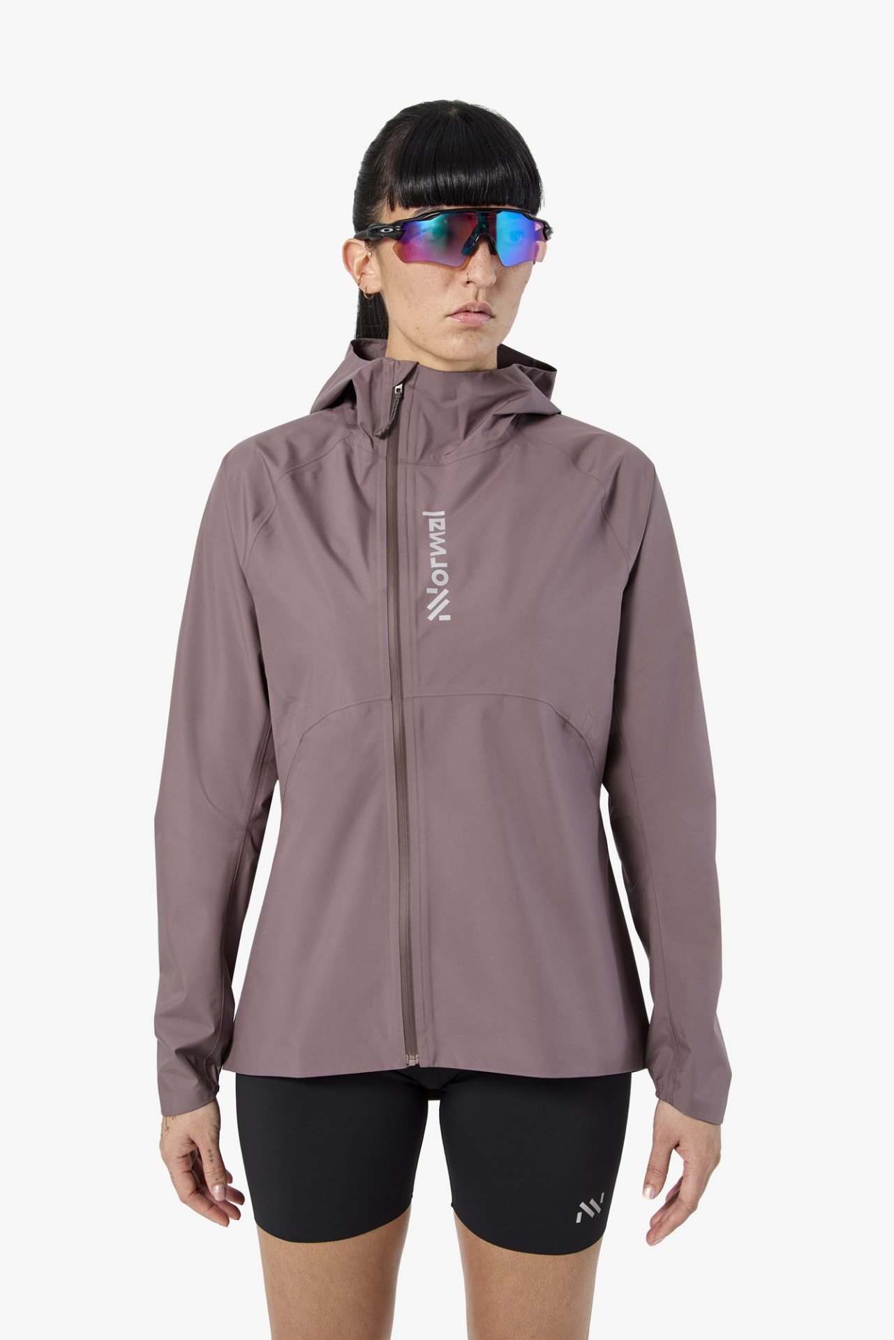 Mulher com corta-vento roxo, óculos de sol esportivos e calções pretos