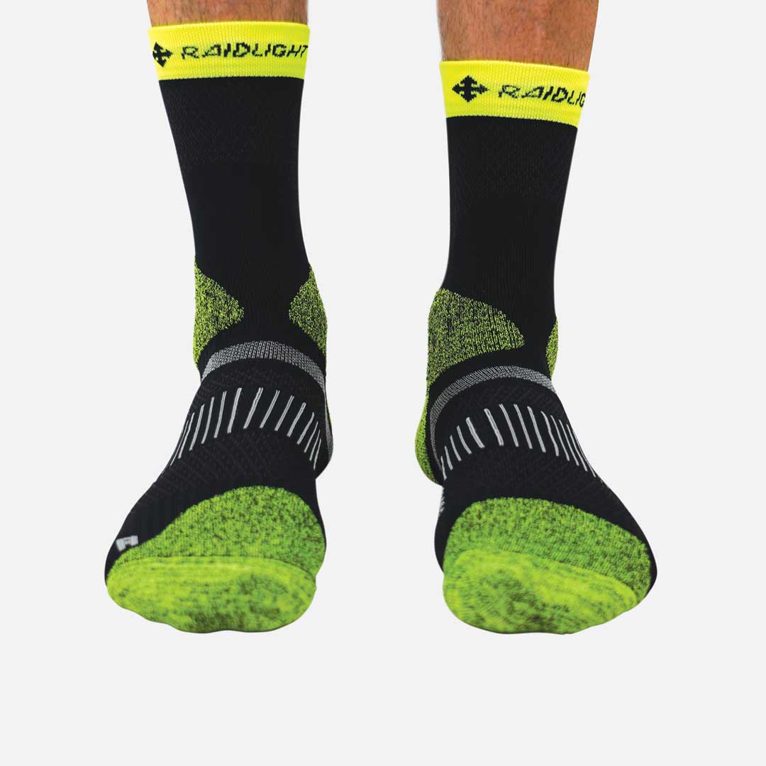 Meias desportivas pretas com detalhes em verde fluorescente e amarelo, topo com texto RAIDLIGHT.