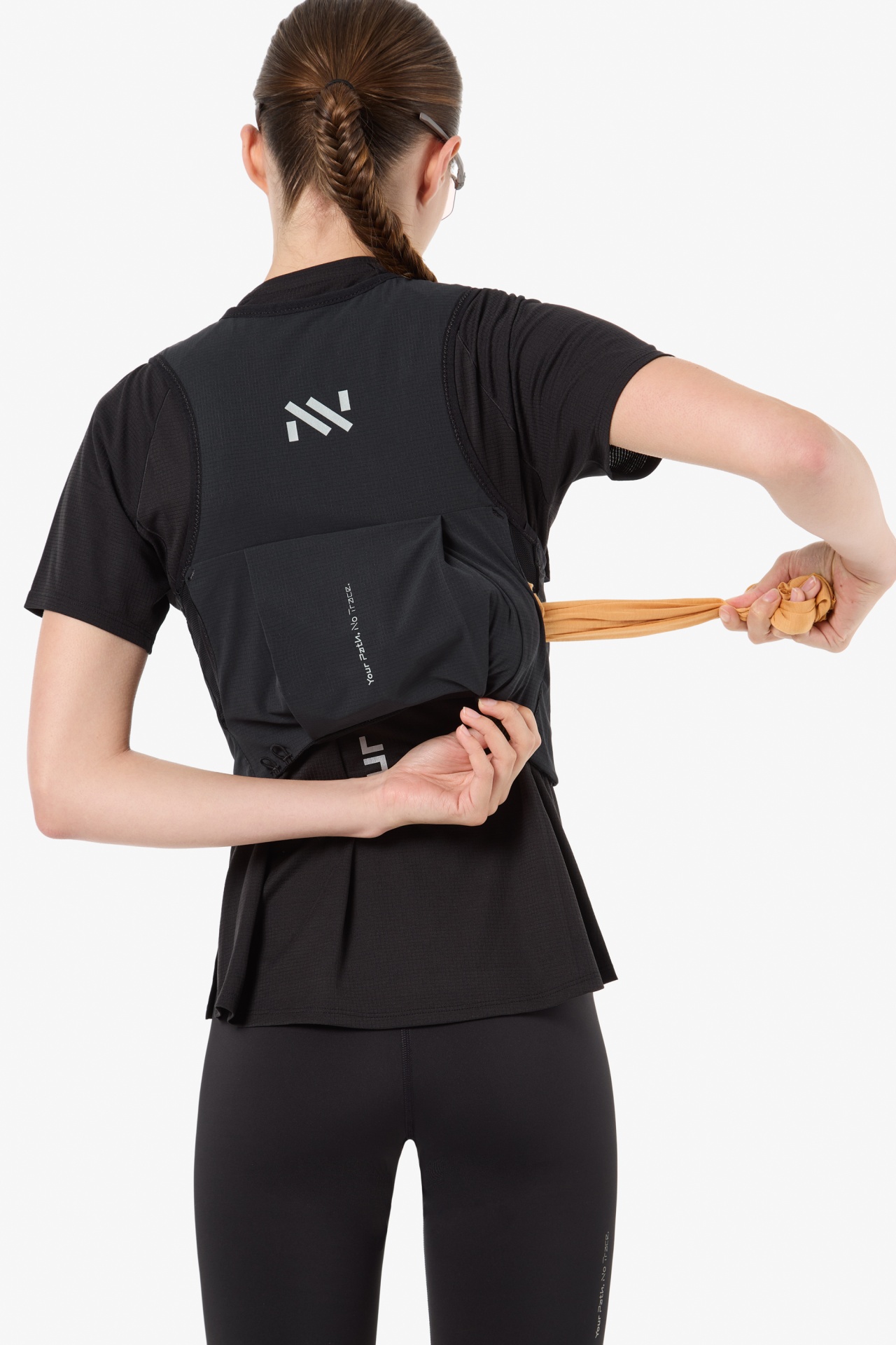 Pessoa de costas com roupa desportiva preta e colete com texto a puxar tecido laranja