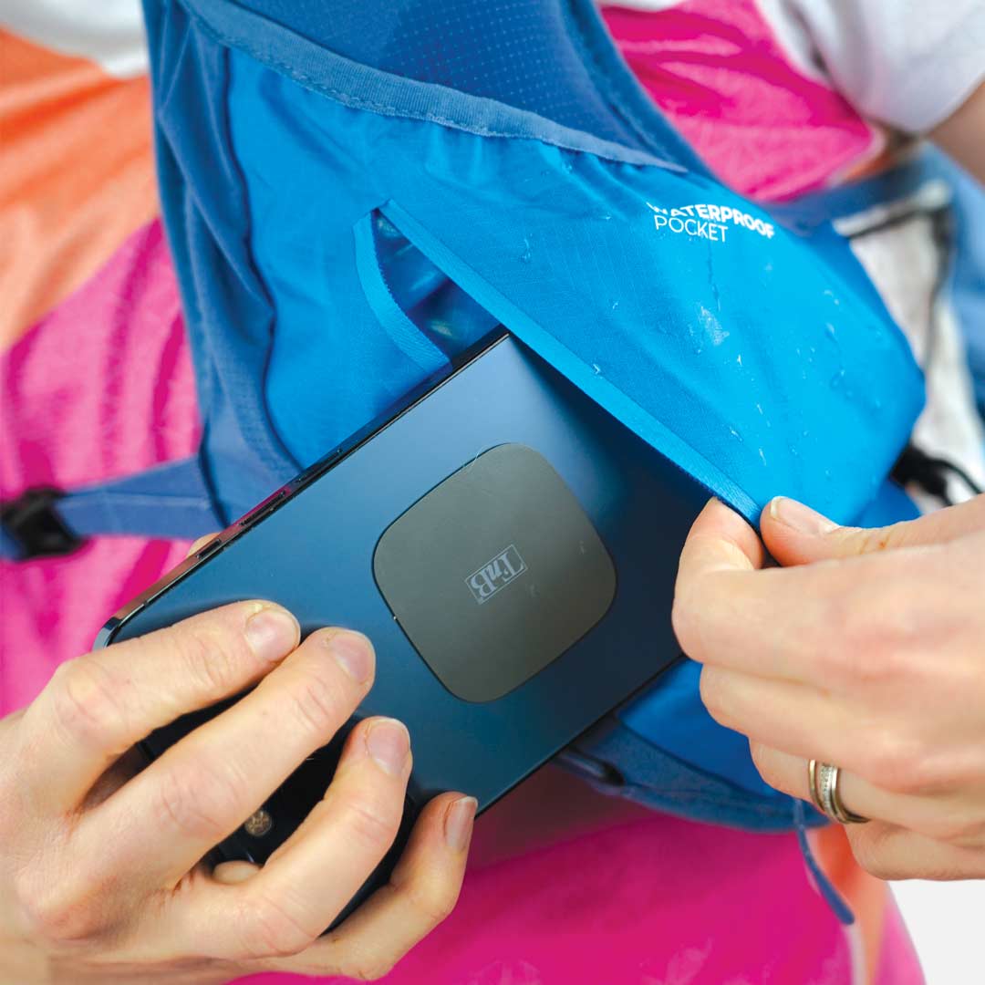 Mochila azul com bolso impermeável e dispositivo preto sendo guardado