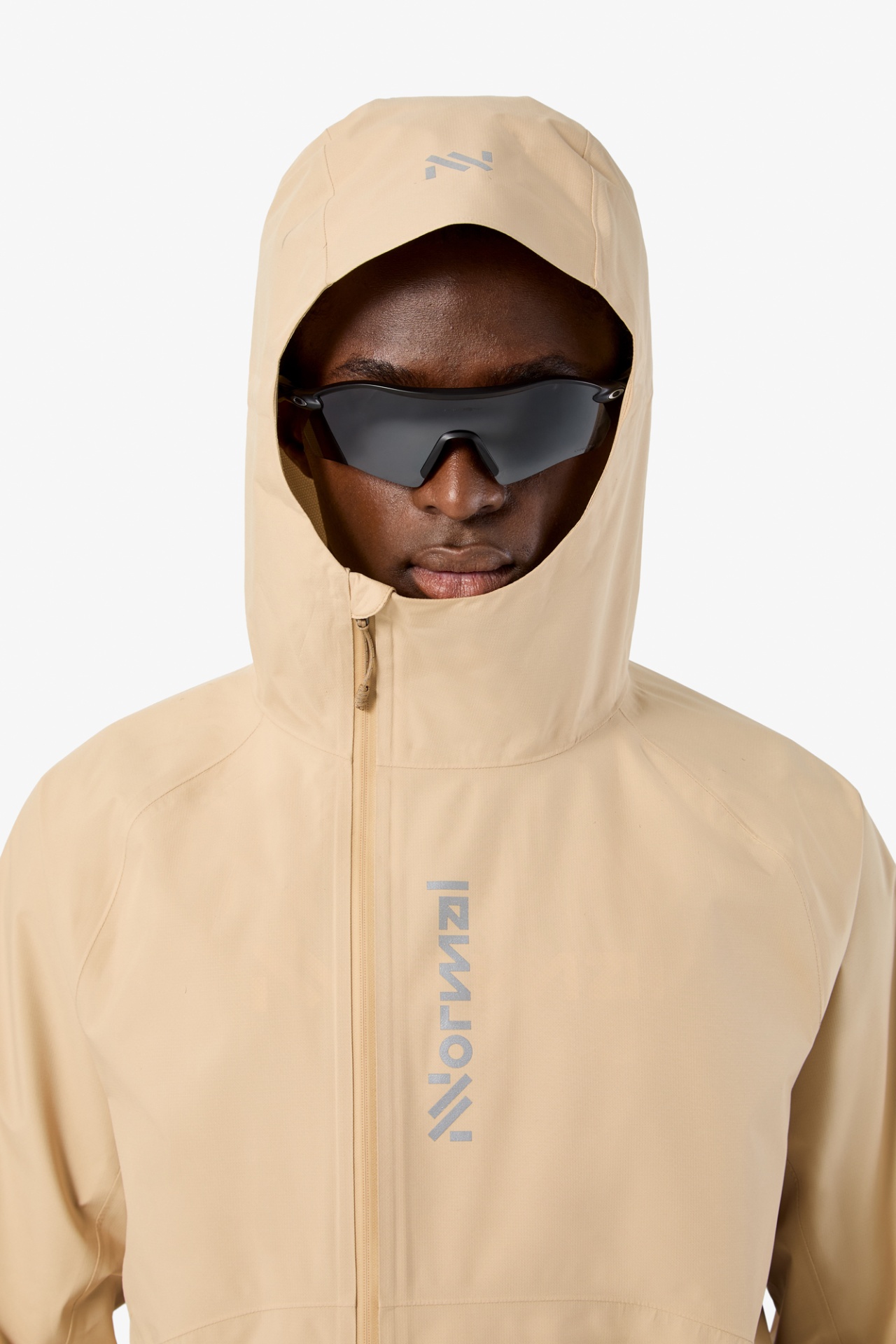 Casaco bege com capuz, zíper frontal e logo Norwid, modelo com óculos de sol pretos