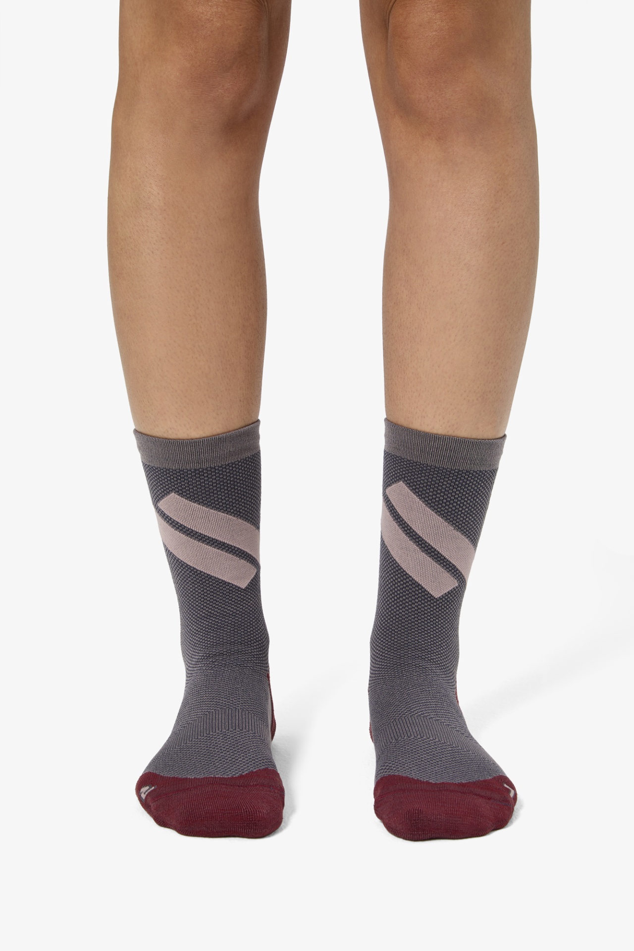 Par de meias cinza com detalhes bordô e faixa rosa em formato de S, usadas em pernas humanas.