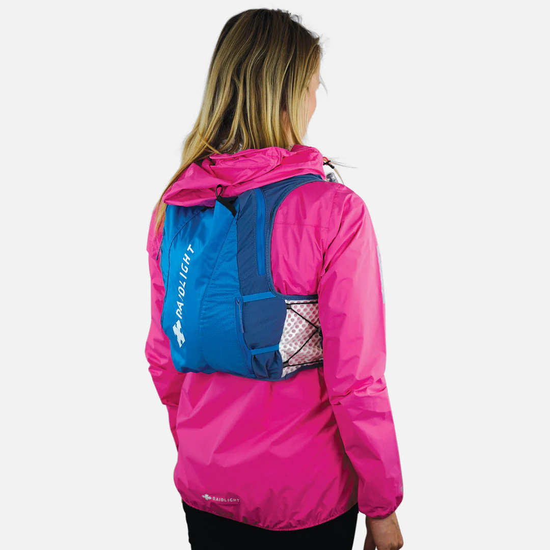 Mochila desportiva azul e azul escuro com texto RAIDLIGHT em pessoa de casaco rosa
