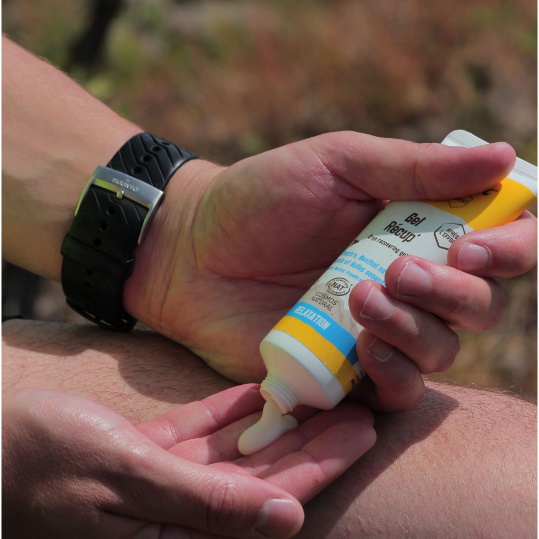 Pessoa aplicando creme das mãos tubo branco amarelo azul com bracelete preta