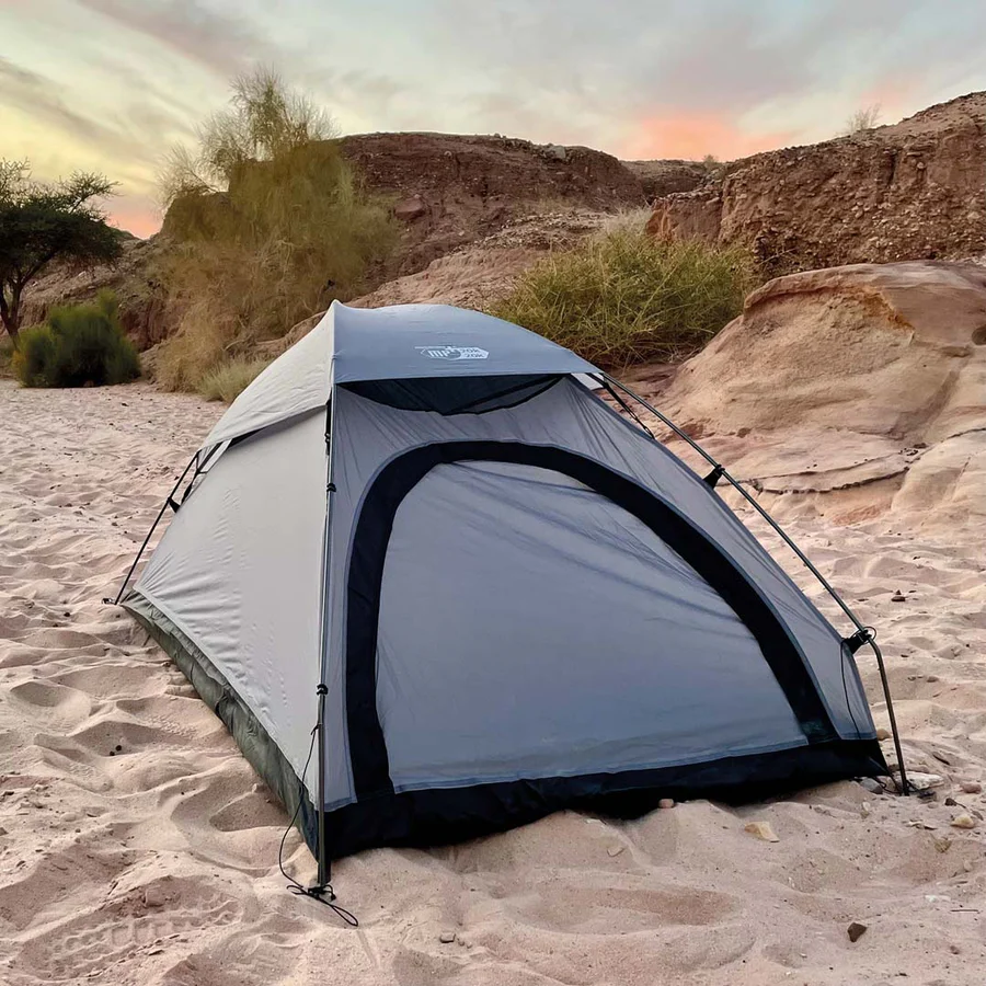 Tenda cinza de campismo com estrutura preta montada na areia