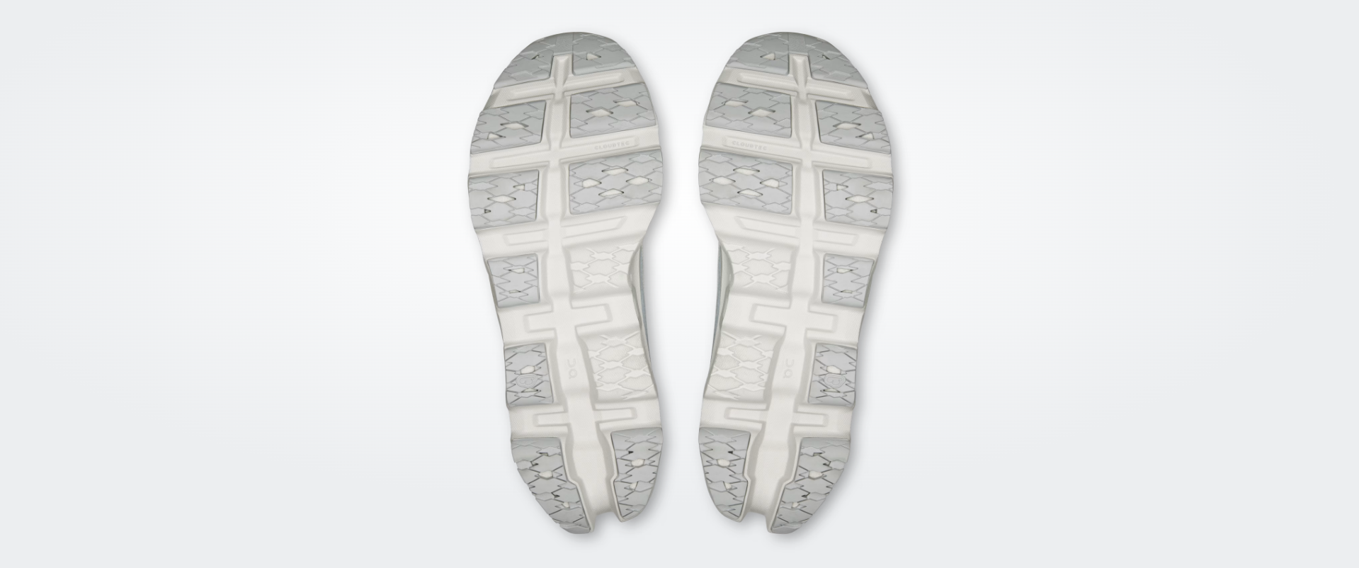 Solas de sapatilhas desportivas brancas e cinzentas com padrão geométrico