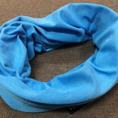 Cachecol tubular azul claro sobre fundo castanho.