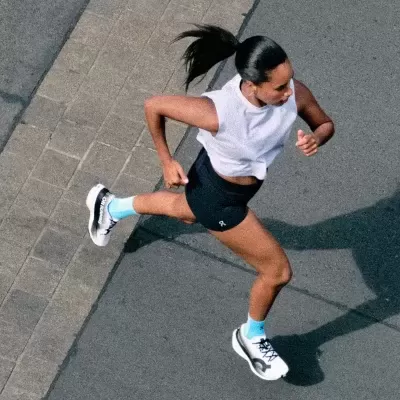 Mulher a correr com roupa desportiva e sapatilhas brancas numa estrada