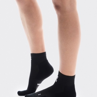 Par de meias pretas com texto branco usadas num pé humano