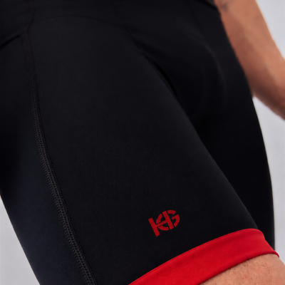 Calções desportivos pretos e vermelhos com logótipo KG na perna.