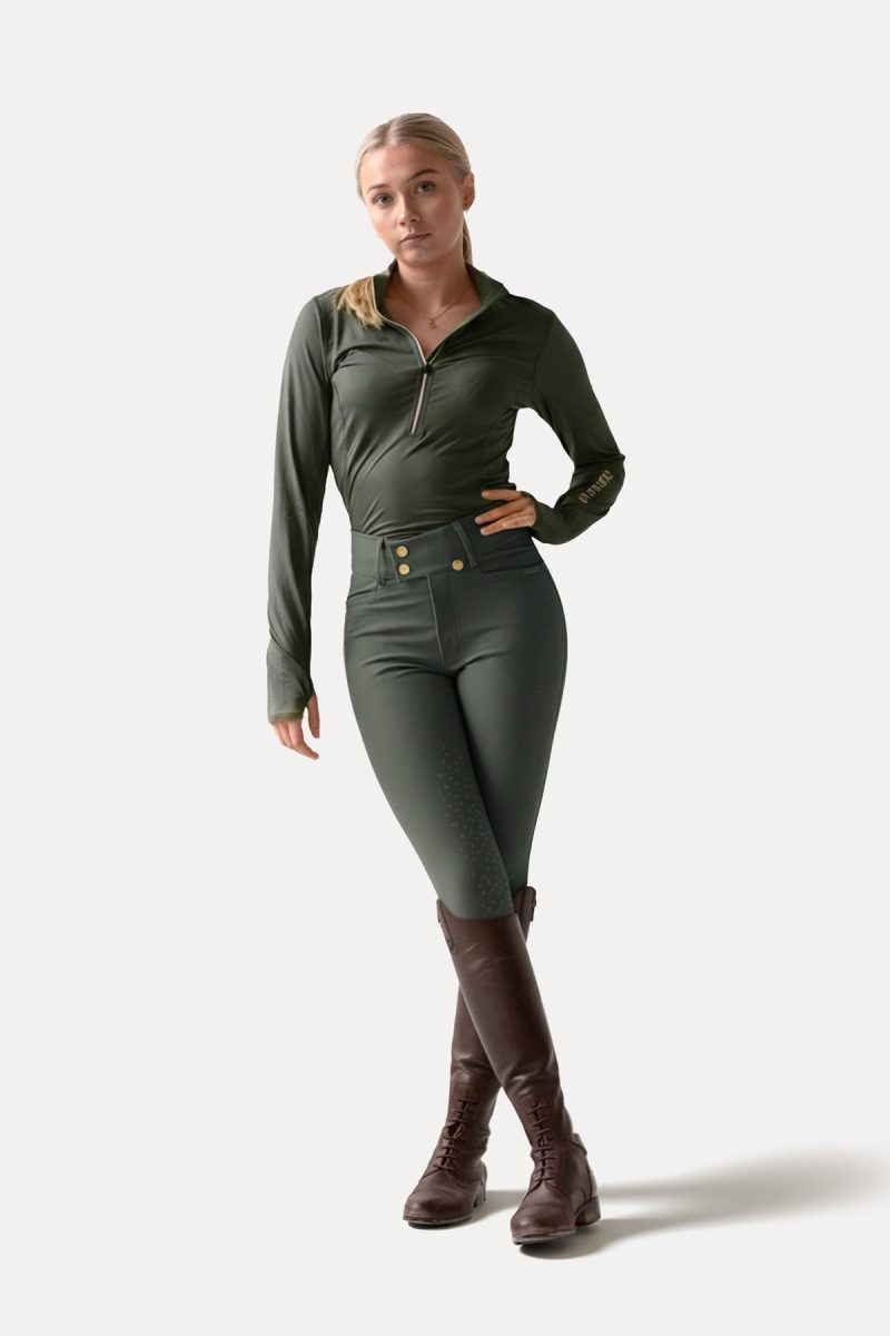 Modelo com roupa desportiva verde escura e botas de montar castanhas