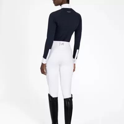 Mulher de costas com roupa de equitação azul, branca e preta