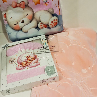 Conjunto de manta e tecidos infantis com estampas de ursinhos e nuvens em tons rosa e azul.
