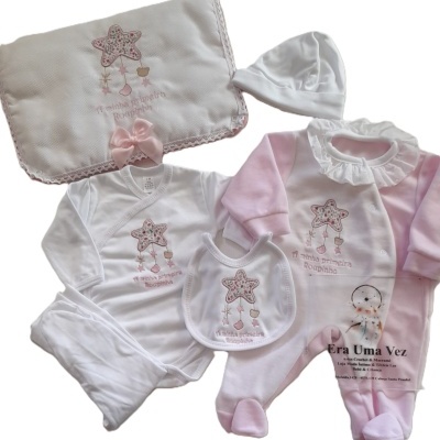 Conjunto de roupa de bebé branco e rosa com bordados de estrela e mantinha branca com laço rosa