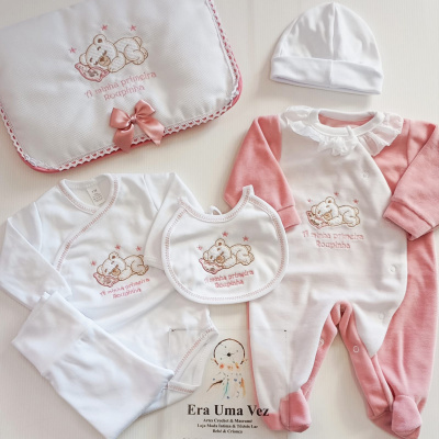 Conjunto de roupa de bebé com urso bordado e texto A minha primeira roupinha em branco e rosa.