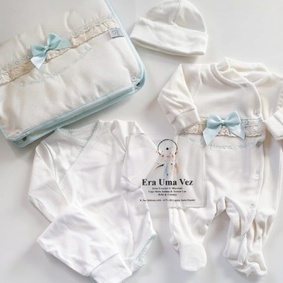 Conjunto de roupa de bebé branco com detalhes em azul e manta decorada com renda e laço azul